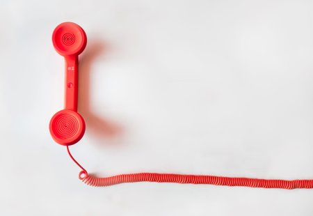 A red wired phone against a white background