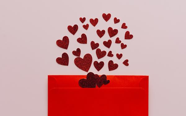 A red envelope with red glitter hearts spilling out