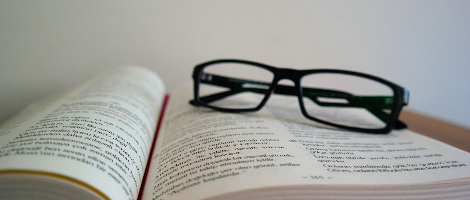 A pair of black glasses sat on top of an open book.