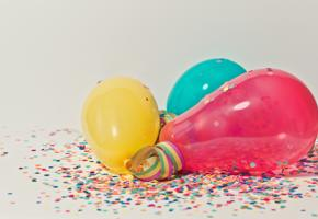 Yellow, teal and pink balloons against a confetti background.