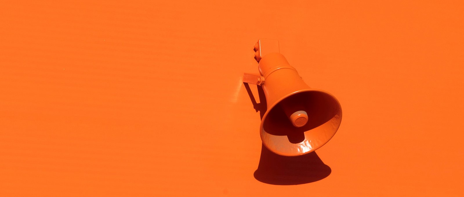 A bright orange megaphone on an orange background