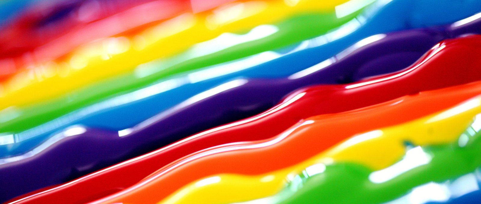 Close up of strands of paint in a rainbow of colours