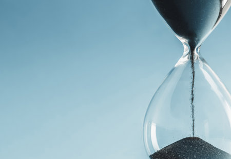 Close-up of black sand flowing down inside an hourglass