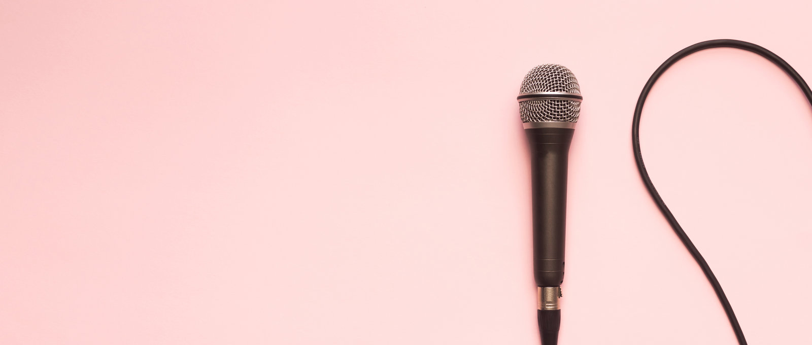 Photograph of a microphone and cable on a pink surface